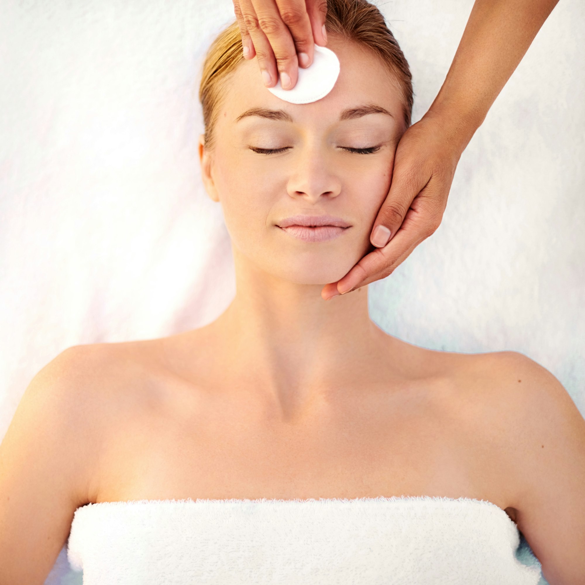Starting her facial with a gentle cleanser. Shot of a young woman getting a facial at a spa.