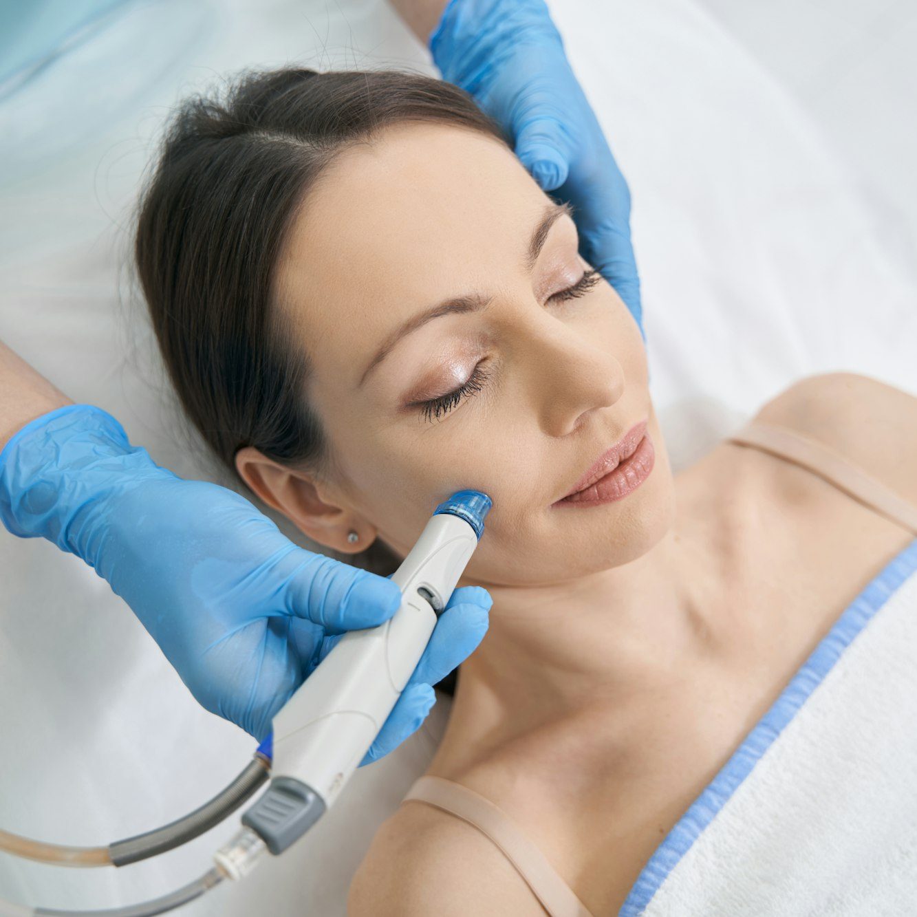 Woman receiving hydrafacial treatment in beauty salon